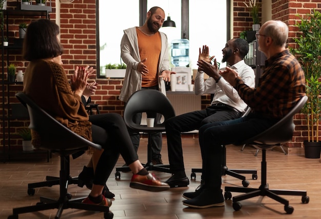 Aa meeting group of people applauding man with addiction\
progress, sitting in circle and celebrating achievement. patients\
at therapy session clapping hands and congratulating progress.