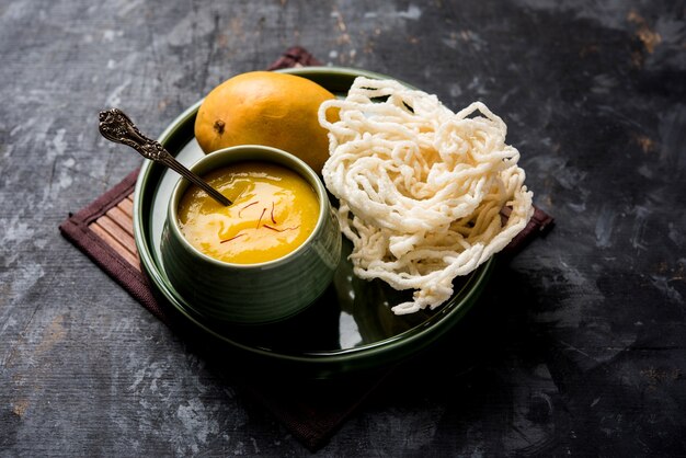 Aam Ras or Alphonso mango pulp with kurdai which is a fried dish made using wheat or gehu. selective focus