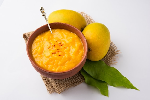 Aam Ras is een heerlijk Indiaas seizoensgebonden dessertrecept, Aamras is gewone Haapus of Alphonso Mango Puree of Pulp met Saffraan, Kesar-topping. Geserveerd in een terracotta kom over kleurrijke achtergrond.