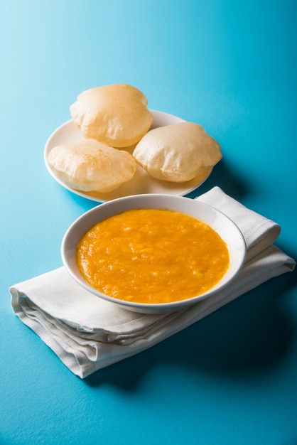 Aam Ras Puri is een heerlijk Indiaas recept dat wordt geserveerd als een seizoensgebonden dessert, Aamras is gewone mangopuree of pulp, geserveerd in een keramische kom en bord op een kleurrijke of houten achtergrond. Selectieve focus