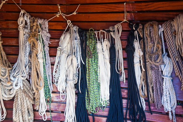 Aan de houten wand van een oud schip hangen veel verschillende touwen die opgerold zijn vastgebonden