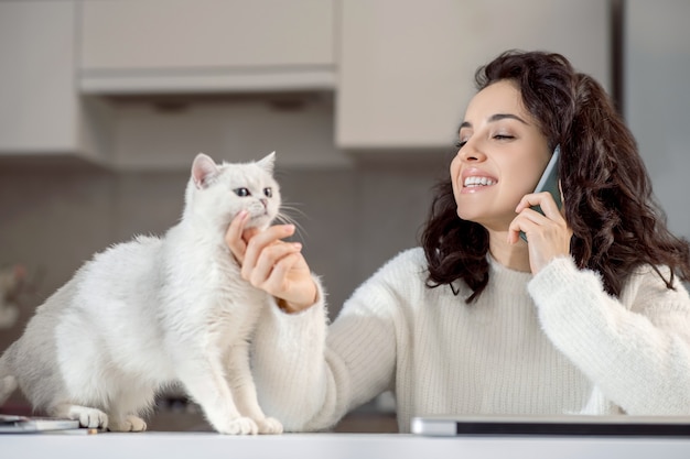 Aan de telefoon. Glimlachende jonge vrouw die aan de telefoon spreekt en gelukkig kijkt