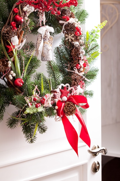 Aan de witte deuren hangt een kerstkrans. rode en witte elementen, strik voor het decoreren van vakantiehuis