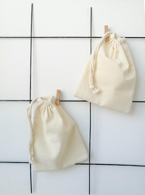 Foto aan een standaard hangt een wit katoenen zakje met wasknijpers aan de muur