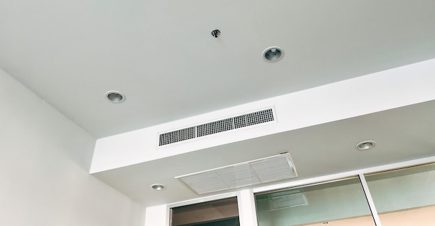 Aan het plafond gemonteerde cassette-airconditioner en modern lamplicht op wit plafond Duct-airconditioner voor thuishal of kantoor