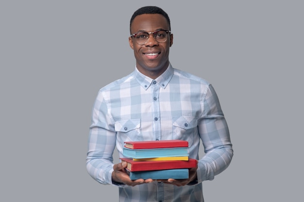 Aan het studeren. een man met een donkere huidskleur in een geruit overhemd met boeken