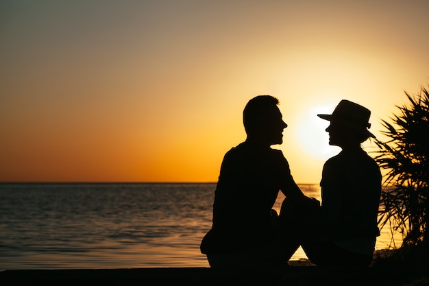 Aanbeden door een verliefd stel aan de kust die bij zonsondergang van elkaar genieten