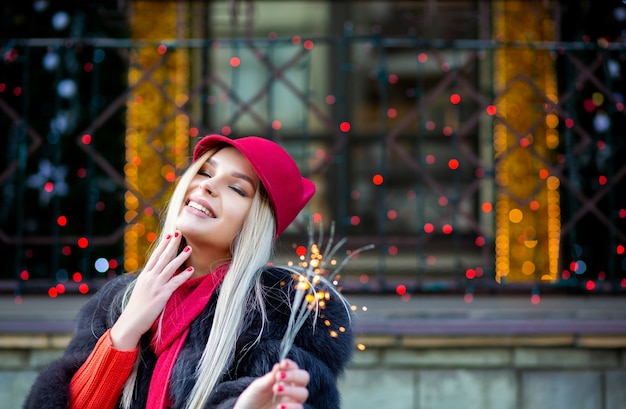 Aanbiddelijk blond meisje dat nieuwjaar viert met sterretjes bij de wazige stadslichten. ruimte voor tekst