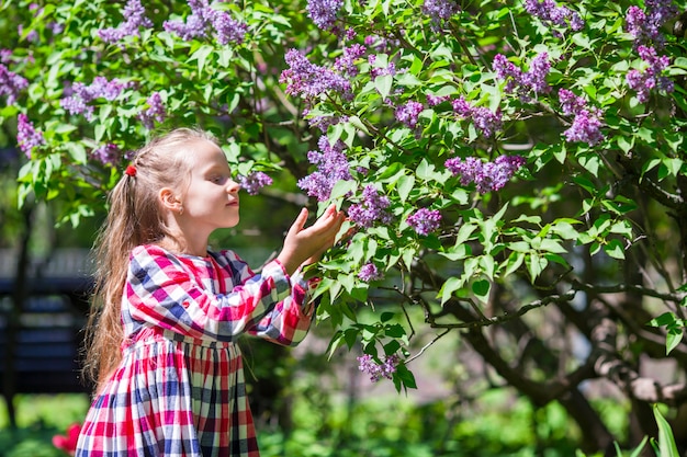 Aanbiddelijk gelukkig meisje met mand in lilac bloementuin