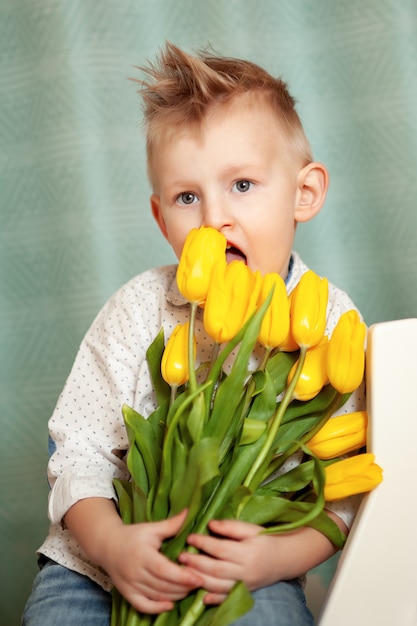 Aanbiddelijk glimlachend kind met het boeket van de de lentebloem.