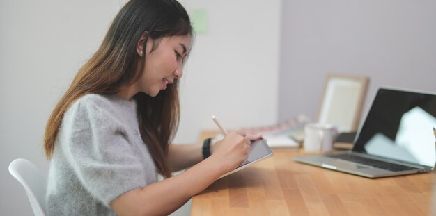 Aanbiddelijk jong wijfje die freelancer haar ideeconcept op tablet schrijven