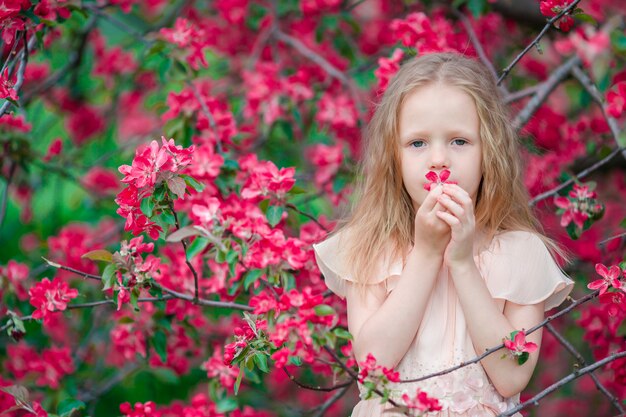 Aanbiddelijk meisje die de lente van dag in appel bloeiende tuin genieten