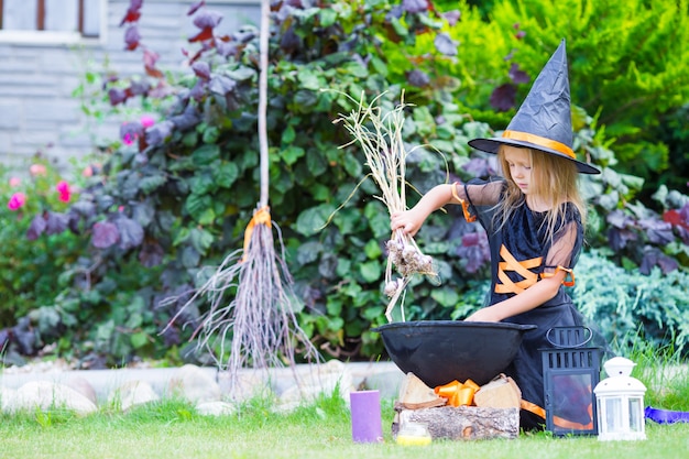 Aanbiddelijk meisje die heksenkostuum met bezem op Halloween in openlucht dragen