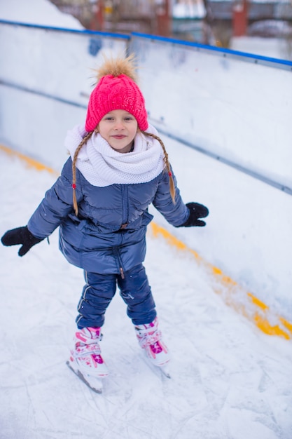 Aanbiddelijk meisje die op de ijsbaan schaatsen