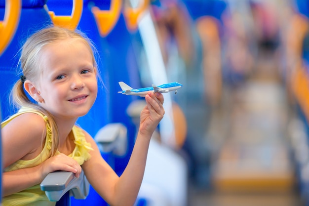 Aanbiddelijk meisje die op trein reizen en pret met vliegtuigmodel hebben in handen