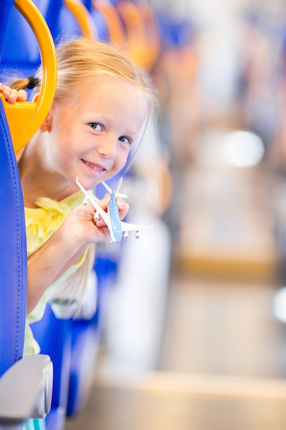 Aanbiddelijk meisje die op trein reizen en pret met vliegtuigmodel hebben in handen