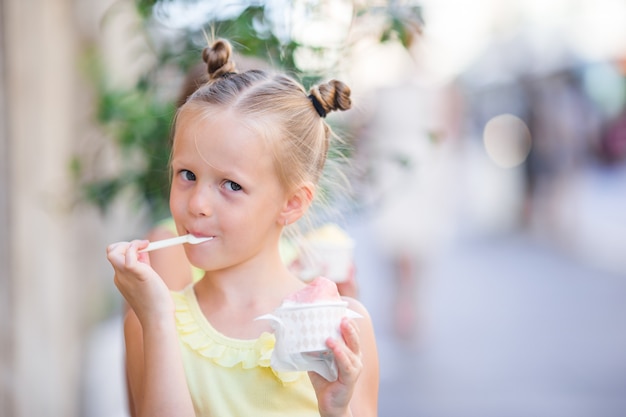 Aanbiddelijk meisje die roomijs in openlucht eten bij de zomer.