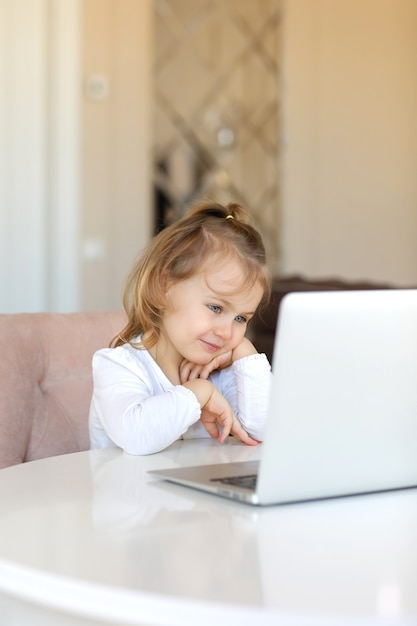 Aanbiddelijk meisje gebruikt een laptopvideochat voor online communicatie thuis. Kind online