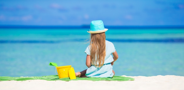 Aanbiddelijk meisje in hoed bij strand tijdens de zomervakantie