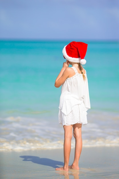 Aanbiddelijk meisje in kerstmanhoed op tropisch strand