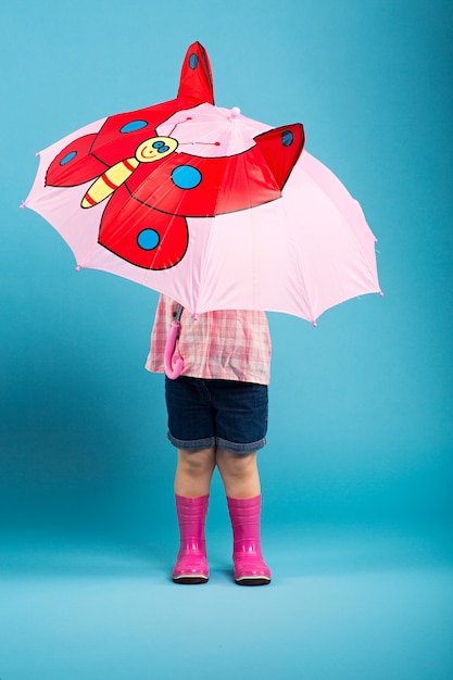 Aanbiddelijk meisje met roze paraplu op blauwe achtergrond