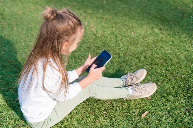 Aanbiddelijk meisje met telefoon tijdens de zomervakantie in openlucht