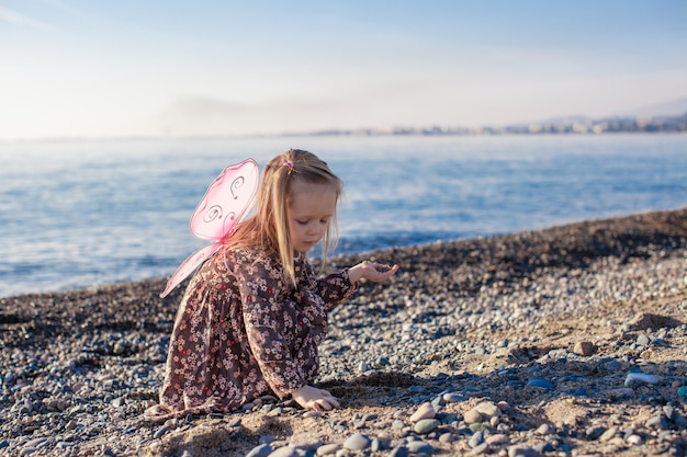 Aanbiddelijk meisje spelen op het strand in een zonnige winterdag