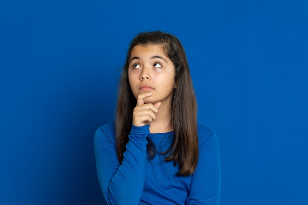 Aanbiddelijk Preteen-meisje met het blauwe gesturing van Jersey over blauwe muur