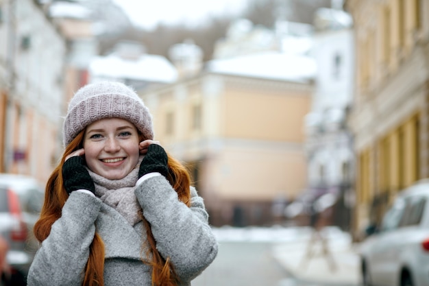 Aanbiddelijk roodharig meisje dat warme winterkleren draagt en door de straat loopt. Ruimte voor tekst