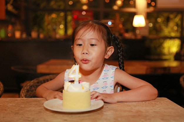 Aanbiddelijk weinig Aziatisch kindmeisje die gelukkige verjaardagscake 4 jaar blazen oud.