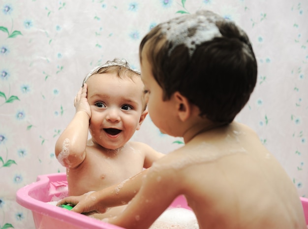 Aanbiddelijke babyjongen die een bad met zeepzeepsop op haar neemt