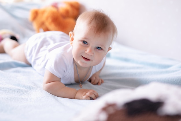 Aanbiddelijke babyjongen in witte zonnige slaapkamer. Het pasgeboren kind ontspannen op een blauw bed. Kinderkamer voor jonge kinderen.