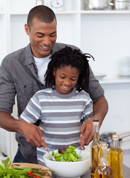 Aanbiddelijke kleine jongen die salade met zijn vader voorbereidt