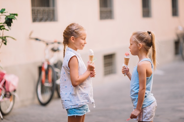 Aanbiddelijke meisjes die roomijs in openlucht eten bij de zomer.