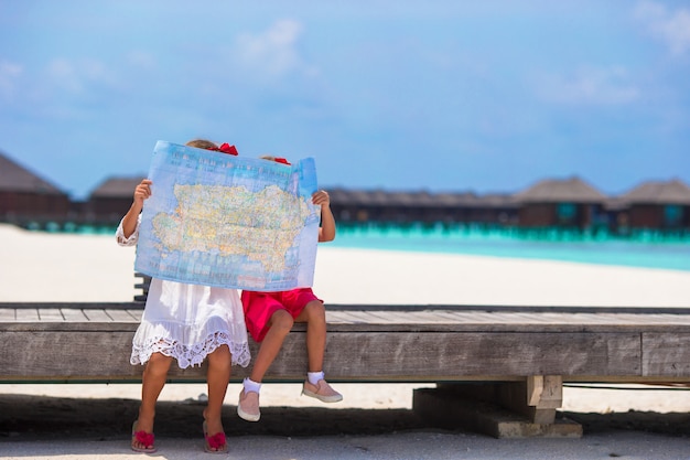 Aanbiddelijke meisjes met kaart van eiland op strand