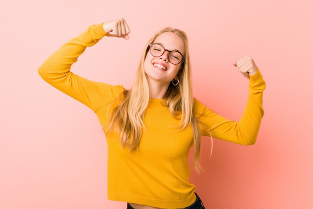 Aanbiddelijke tienervrouw die sterktegebaar met wapens tonen, symbool van vrouwelijke macht