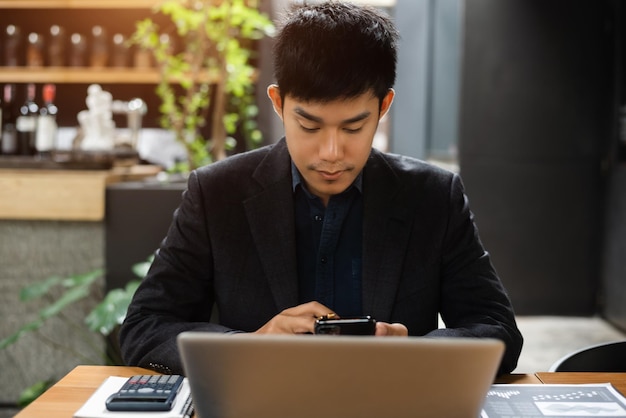 Aangenaam uitziende succesvolle professionele mannelijke bedrijfsaccountant leert dat de zaak van klanten werkt op laptop en smartphone