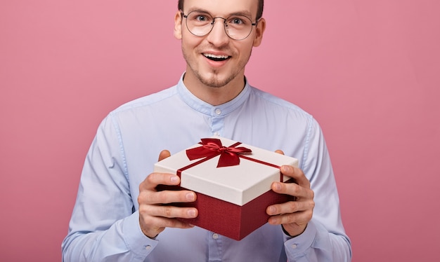 Aangenaam verrast man houdt geschenk in doos met rode deksel