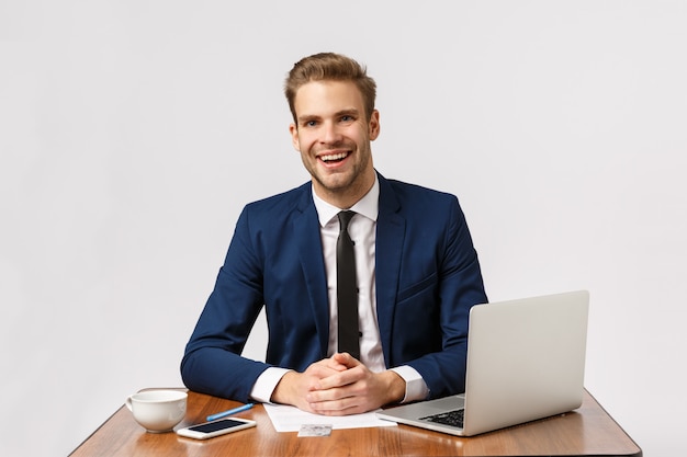 Aangename charmante zakenman met blond haar, baardpak, zittend kantoor met rapport, laptop, lachende vriendelijke consulting client, zakelijk gesprek met werknemers, witte achtergrond