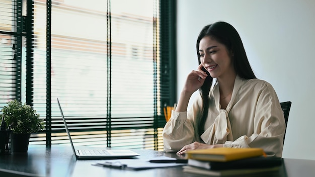 Aangename jonge vrouw ondernemer werkt op laptopcomputer op moderne werkplek