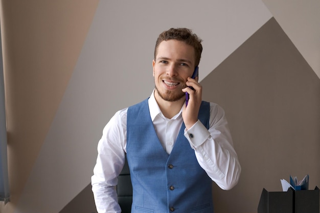 Aangename knappe bebaarde man in shirt en vest praten over telefonisch bestellen