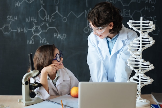 Aangename samenwerking met vriend. Gelukkig vrolijk lachende leerlingen staan in het lab en verkennen van de wetenschap terwijl ze aan het project werken en gadgets gebruiken