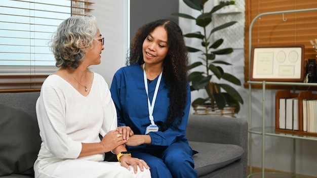 Aangename vrouwelijke verzorger die met een oudere vrouw praat Assistentie, rehabilitatie en gezondheidsconcept