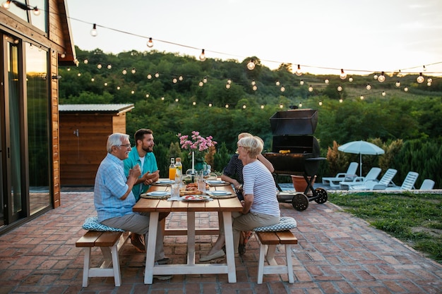 Foto aanhankelijk gezin geniet van het diner tijdens hun bijeenkomst in de achtertuin