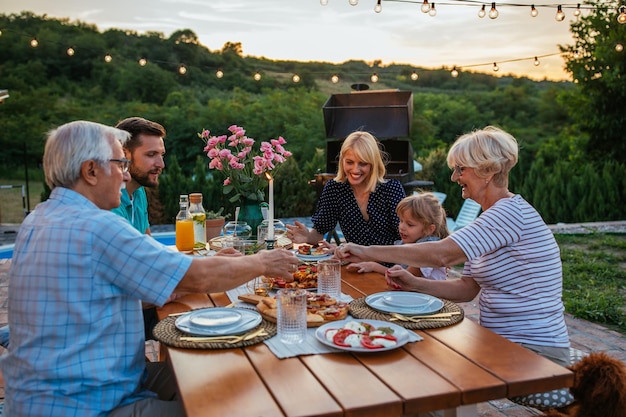Aanhankelijk gezin geniet van het diner tijdens hun bijeenkomst in de achtertuin
