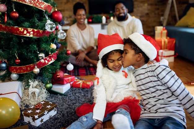 Aanhankelijke zwarte jongen kust zijn zus op eerste kerstdag thuis