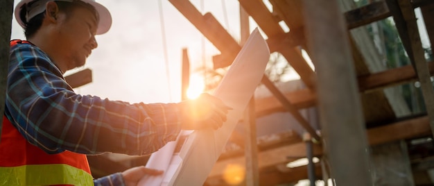 Aannemer man review tekening van het ontwerp nieuwe huisingenieurs lezen de details van de constructie op Tekening vergelijken ter plaatse actueel Concept burgerlijk ingenieur en inspecteur