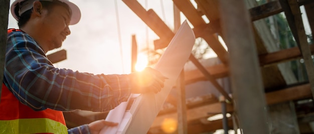 Foto aannemer man review tekening van het ontwerp nieuwe huisingenieurs lezen de details van de constructie op tekening vergelijken ter plaatse actueel concept burgerlijk ingenieur en inspecteur