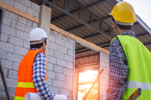 Foto aannemers en ingenieurs staan te praten en samen te werken binnen het bouwgebied