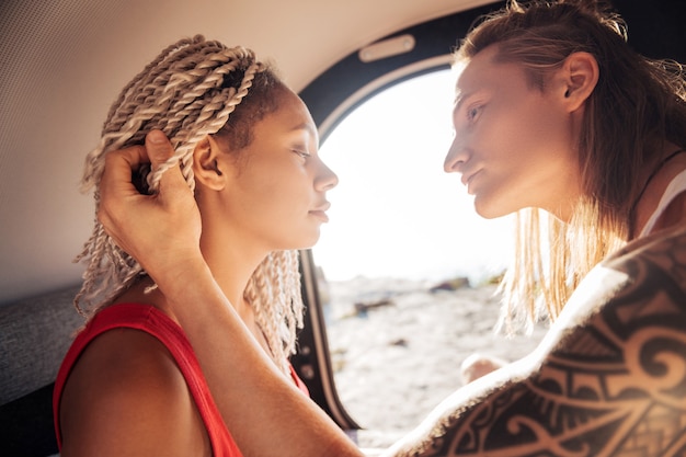 Aanrakende vrouw. Blondharige knappe man raakt zijn mooie vrouw met witte dreadlocks aan